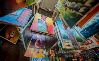 Colorful paintings displayed at a market in Dar es Salaam, featuring wildlife and local scenes.