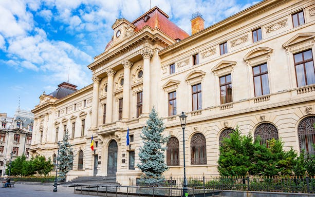 Bucharest Old Town building with neoclassical architecture and Romanian flags.