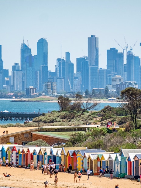 Brighton Beach colorful huts with Melbourne skyline in the background.