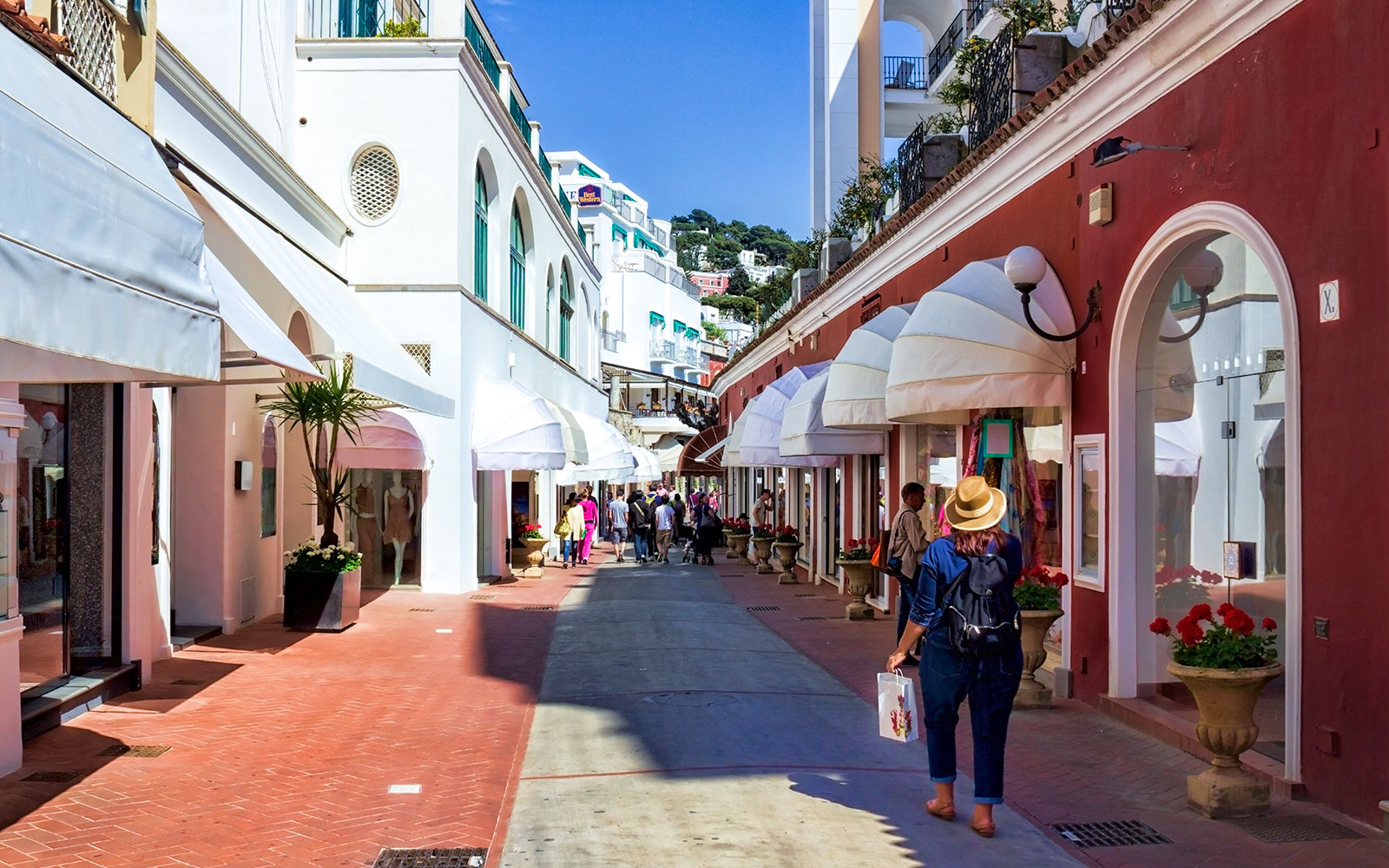 Shoppers walking through a vibrant street in Capri, Italy, lined with boutique stores.
