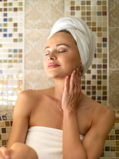 Woman enjoying a steam bath with a towel wrapped around her head.