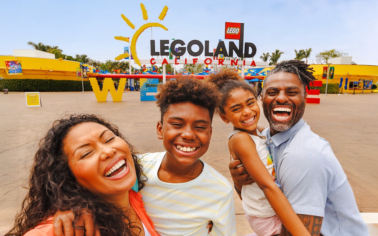 Family smiling at the entrance of LEGOLAND California.