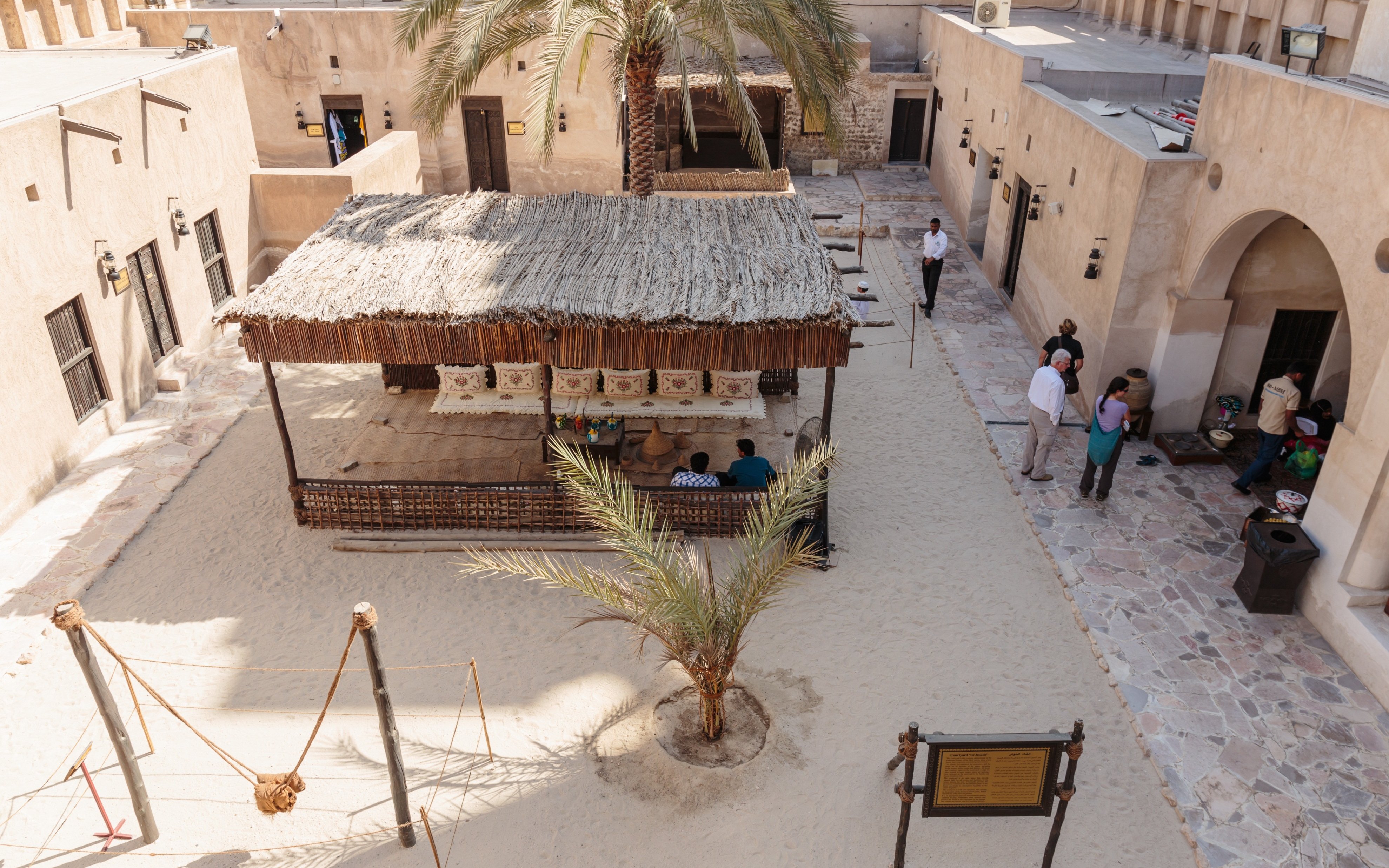 Courtyard in Al Shindagha Historical District, Dubai, with traditional seating and palm trees.