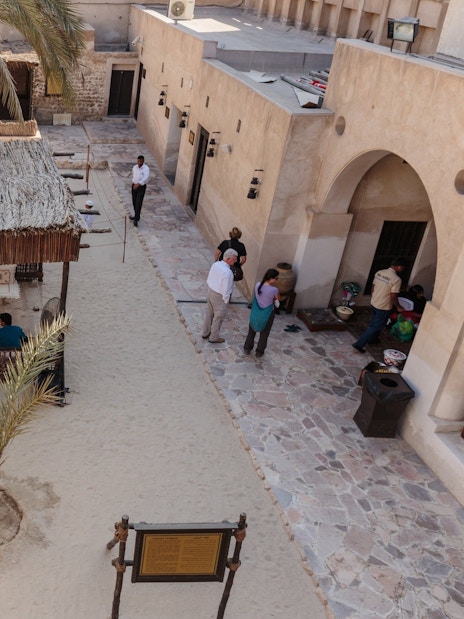 Courtyard in Al Shindagha Historical District, Dubai, with traditional seating and palm trees.