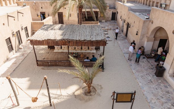 Courtyard in Al Shindagha Historical District, Dubai, with traditional seating and palm trees.