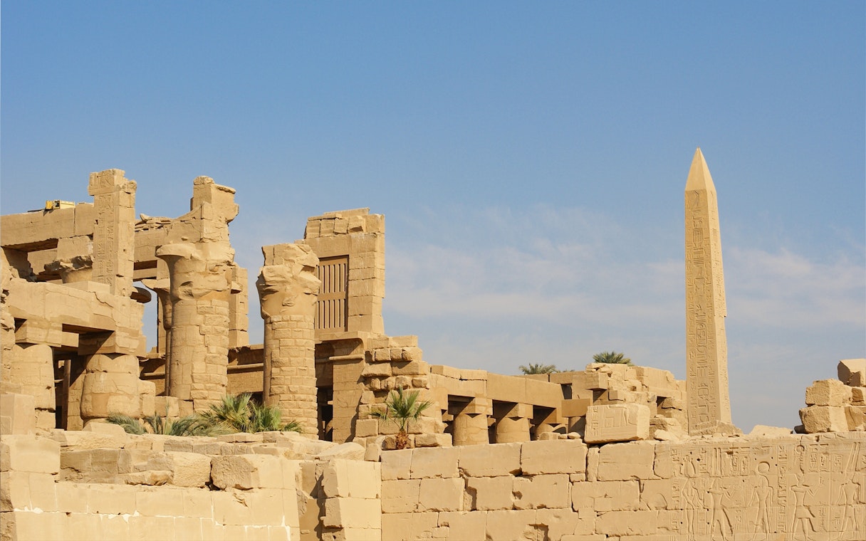 Karnak Temple ruins with ancient columns and obelisk under a clear sky in Luxor, Egypt.