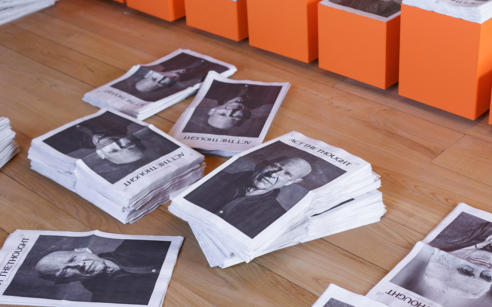 Stacks of newspapers with portraits on the floor at Lello Foundation Museum.