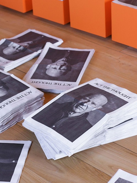 Stacks of newspapers with portraits on the floor at Lello Foundation Museum.