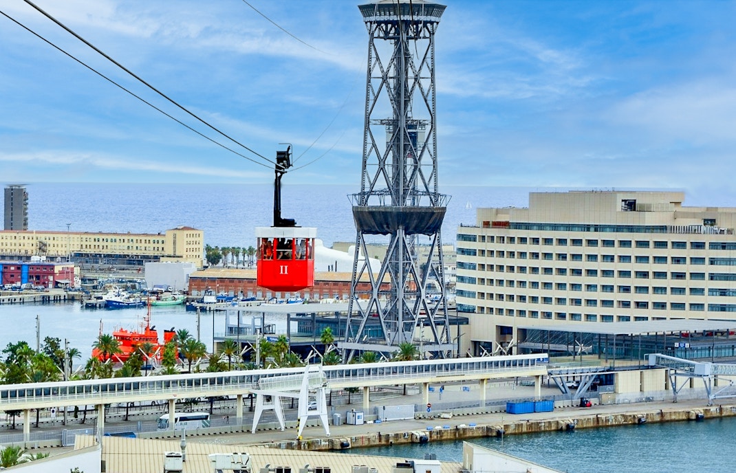 Barcelona skyline view from cable car with catamaran in the harbor, part of walking tour experience.