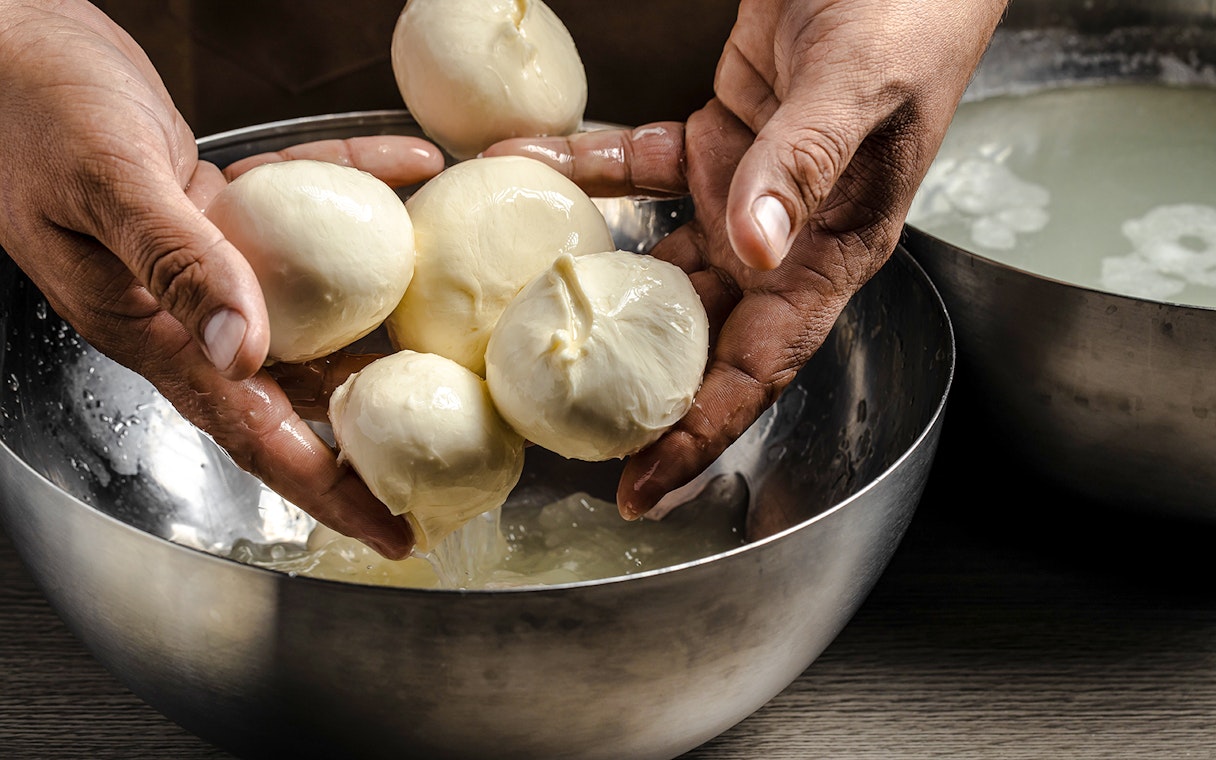 Hands shaping fresh cheese at Cheese Museum in Paris.
