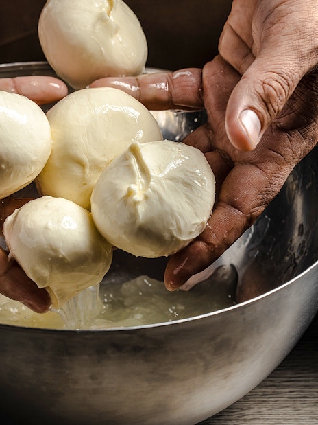 Hands shaping fresh cheese at Cheese Museum in Paris.