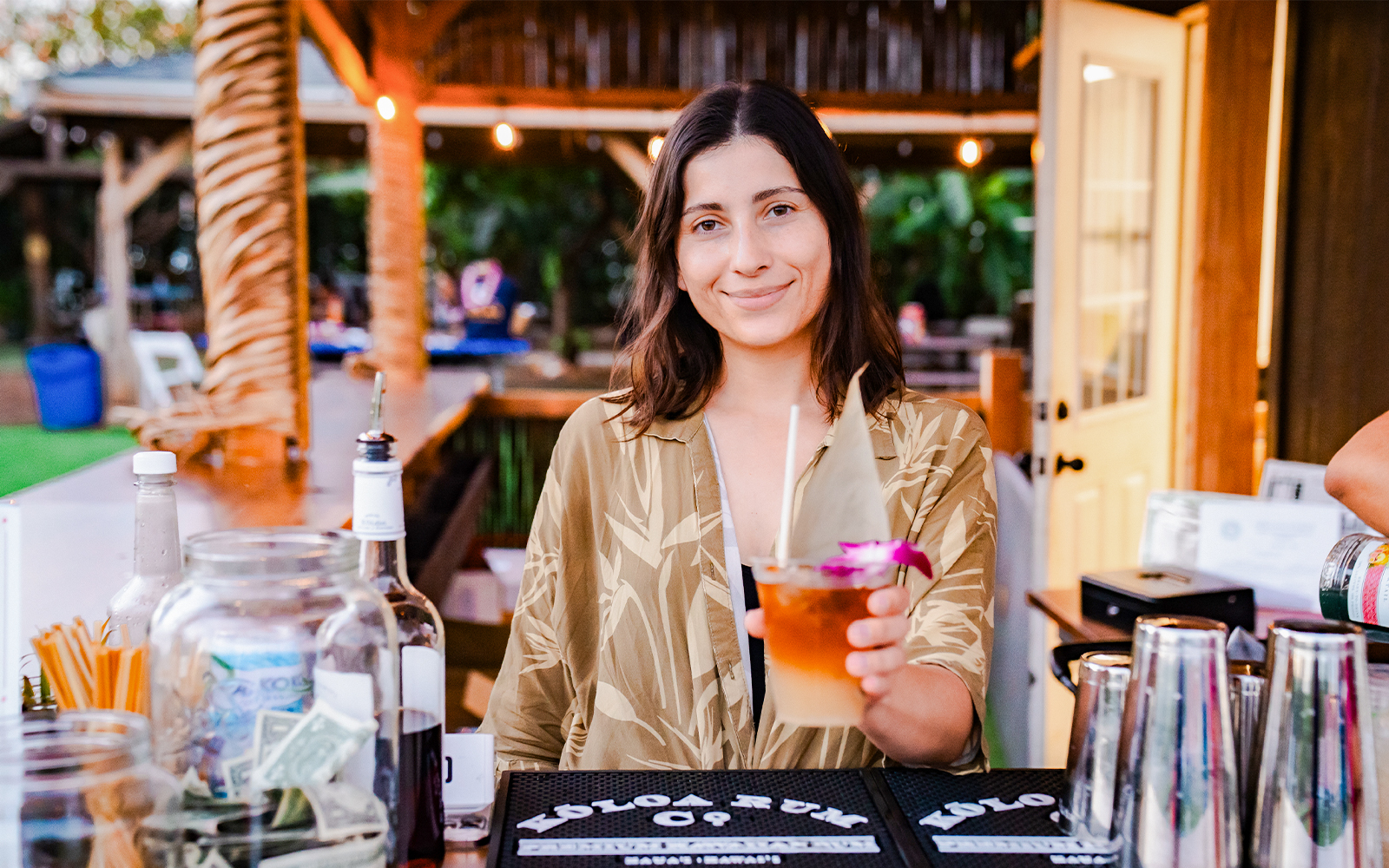 Lady serving traditional Hawaiian drink to guest at Mauka Warriors Luau pre-show activity, Hawaii.
