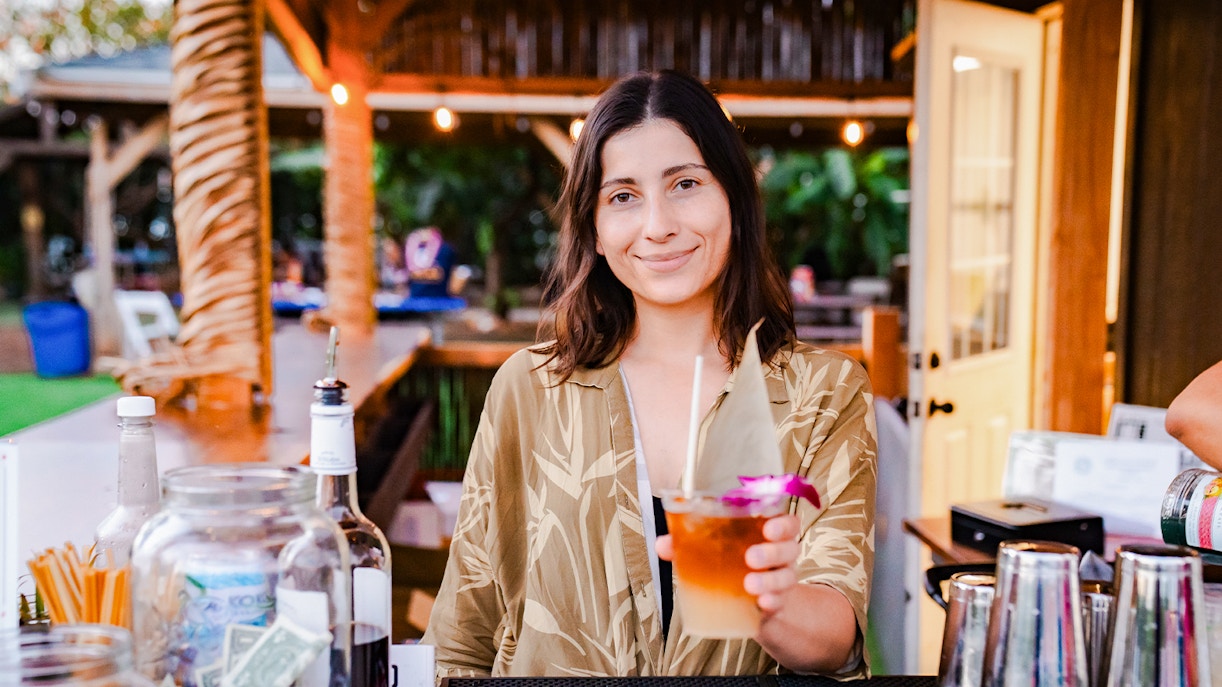 Lady serving traditional Hawaiian drink to guest at Mauka Warriors Luau pre-show activity, Hawaii.