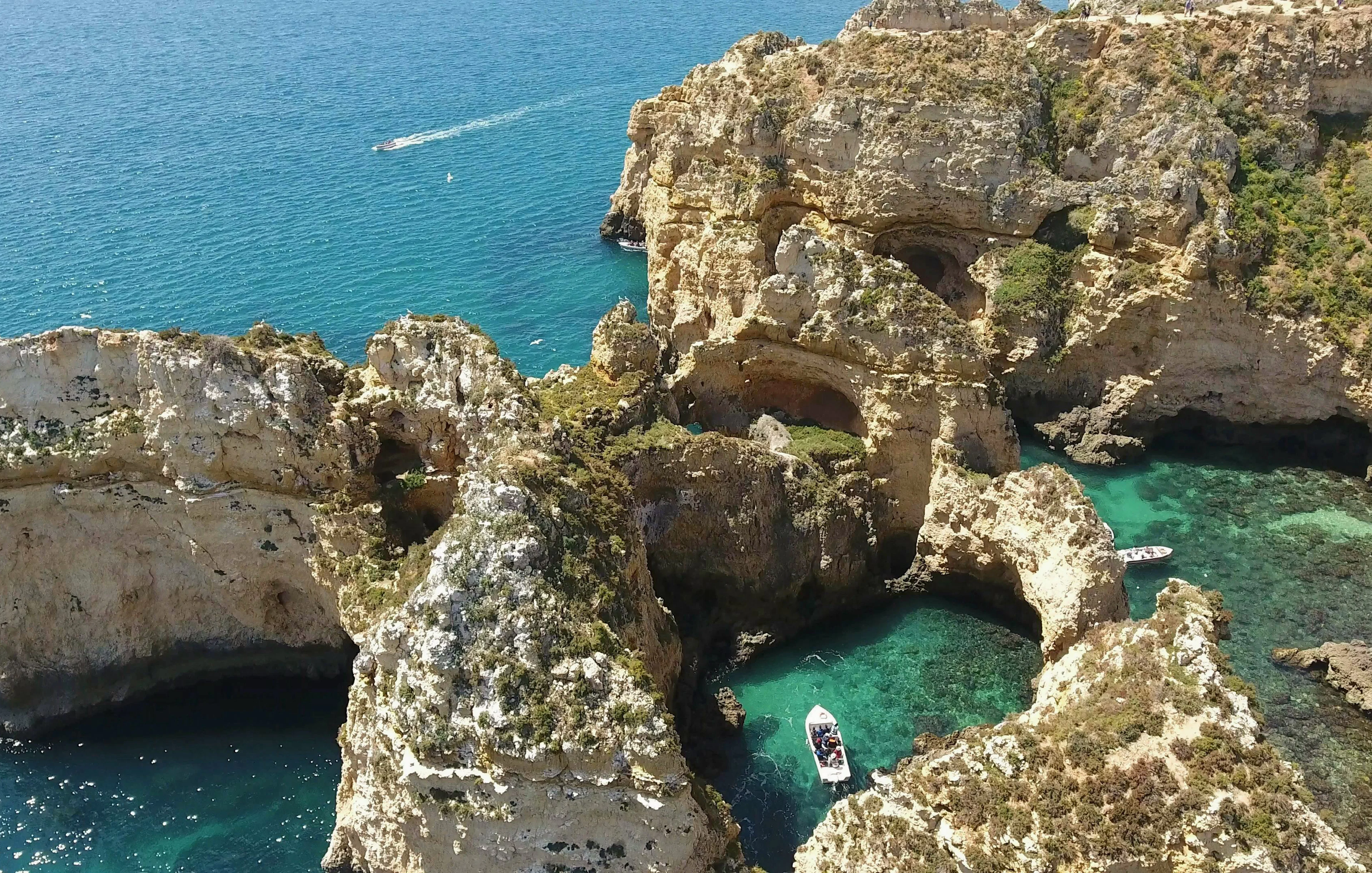 Boat navigating through the rocky cliffs of Ponta da Piedade, Lagos, with turquoise waters.