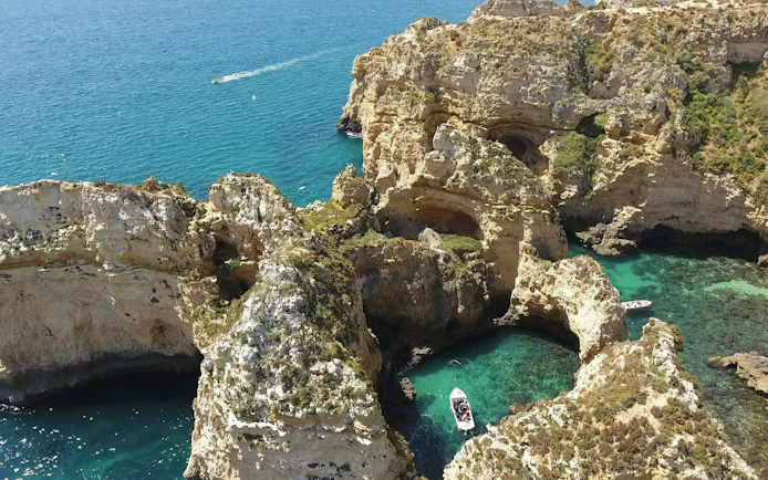 Boat navigating through the rocky cliffs of Ponta da Piedade, Lagos, with turquoise waters.
