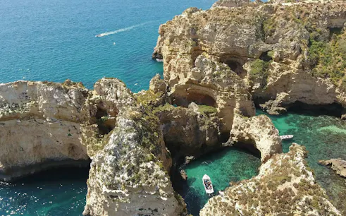 Boat navigating through the rocky cliffs of Ponta da Piedade, Lagos, with turquoise waters.