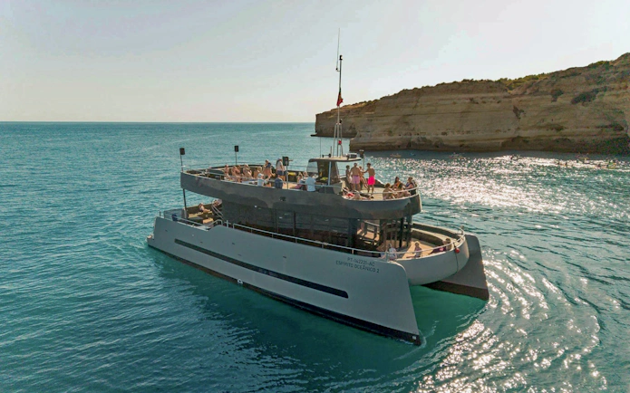 Catamaran with passengers enjoying a sunset cruise near Albufeira, Algarve coast.