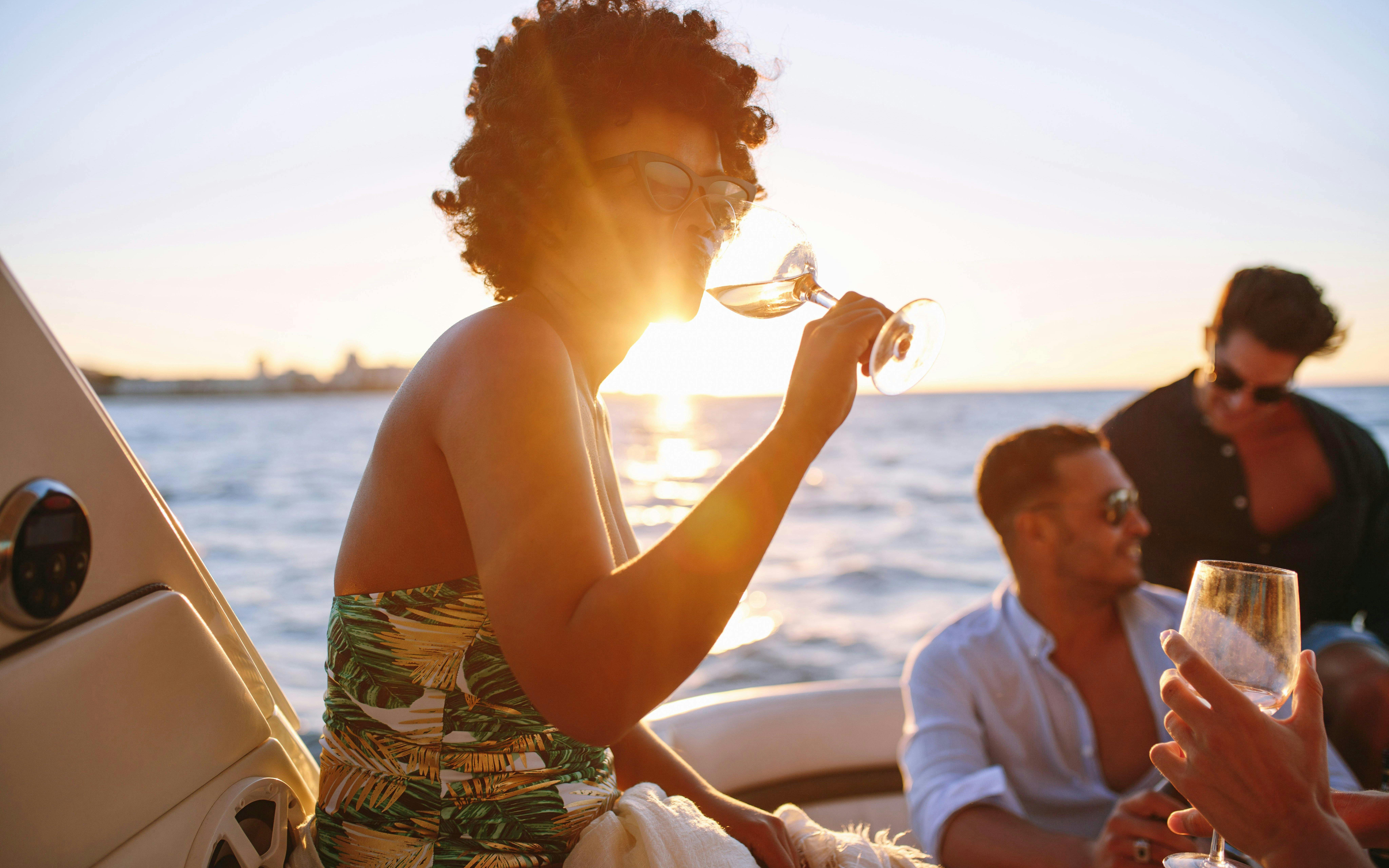 African woman enjoying a drink with friends on a boat during Blue Lagoon cruise from Larnaca.