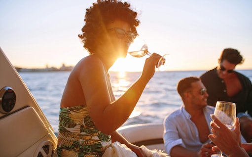 African woman enjoying a drink with friends on a boat during Blue Lagoon cruise from Larnaca.