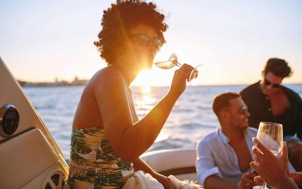 African woman enjoying a drink with friends on a boat during Blue Lagoon cruise from Larnaca.
