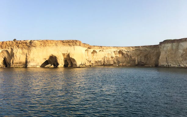 Sea caves along the rocky coastline of Ortigia Island during a sightseeing cruise.
