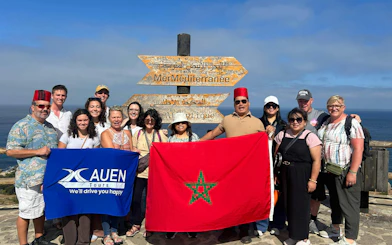 Tour group with guide at Mediterranean and Atlantic Ocean signage in Morocco.