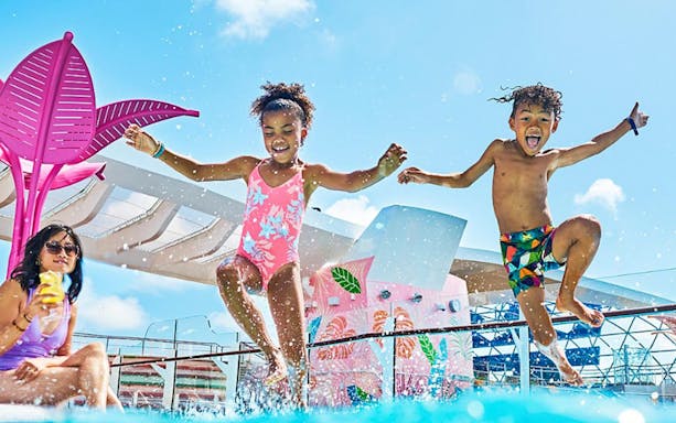 Kids jumping into a cruise ship pool, enjoying water games.