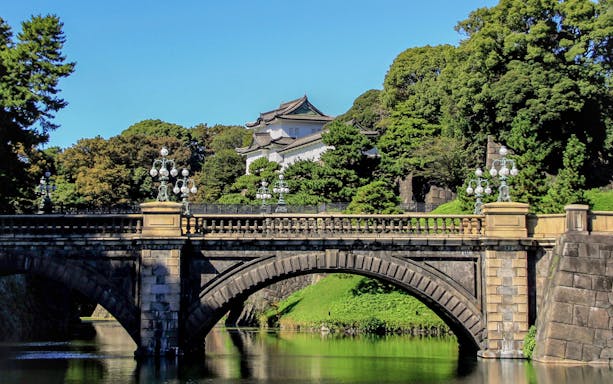 Stone bridge leading to Tokyo's Imperial Palace surrounded by lush greenery.