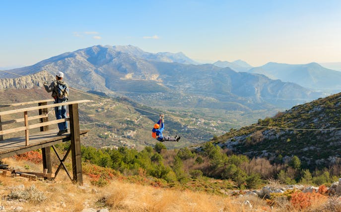 Person ziplining over scenic mountains near Split, Croatia.