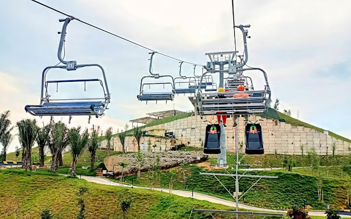 Chairlift ascending to The Skyline Luge in Kuala Lumpur with lush greenery below.