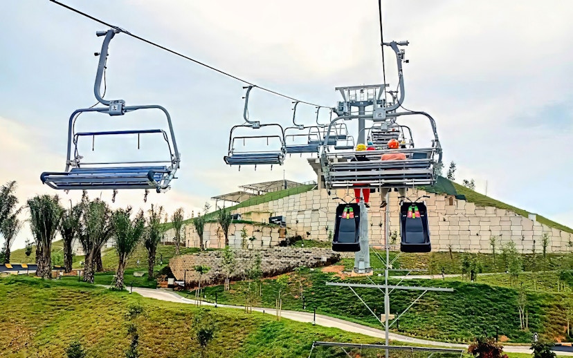 Chairlift ascending to The Skyline Luge in Kuala Lumpur with lush greenery below.
