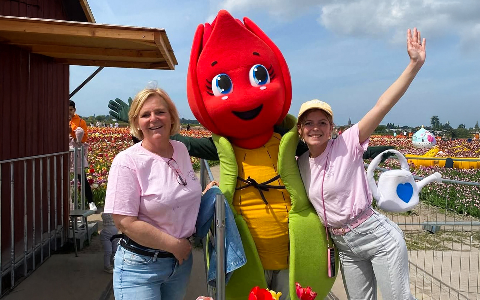 Visitors posing with a tulip mascot in Amsterdam tulip fields during a small group tour.