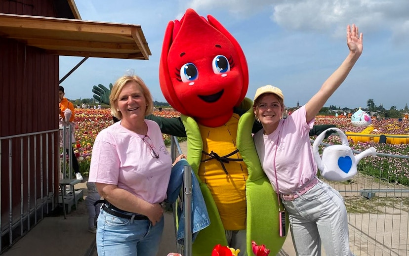 Visitors posing with a tulip mascot in Amsterdam tulip fields during a small group tour.