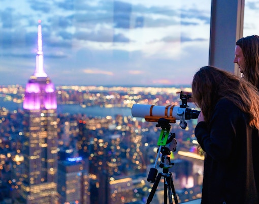 Viewing New York skyline through a telescope at Summit One Vanderbilt during Astronomy Nights.