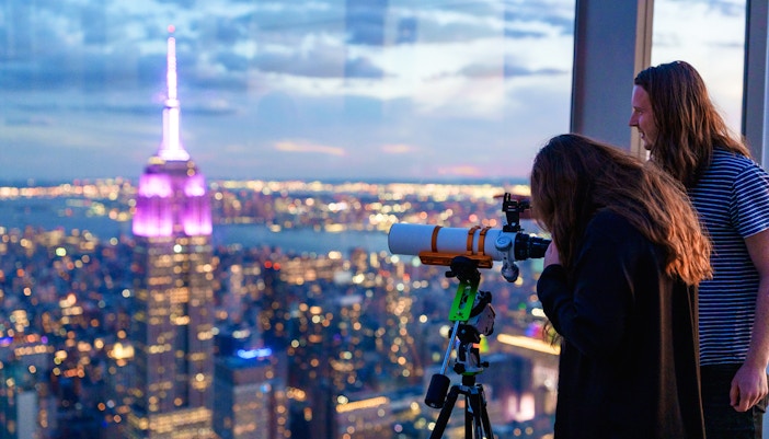 Visitors stargazing through telescopes at Summit One Vanderbilt, New York City, during Astronomy Nights event.