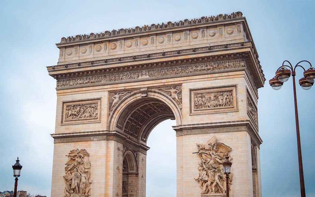 Arc de Triomphe in Paris with detailed sculptures, view from street level.