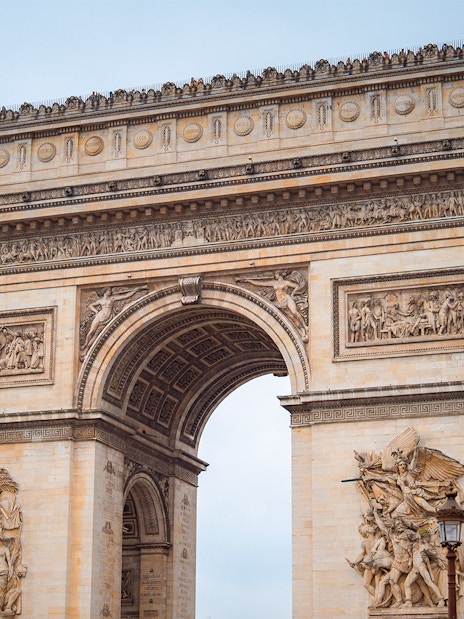 Arc de Triomphe in Paris with detailed sculptures, view from street level.