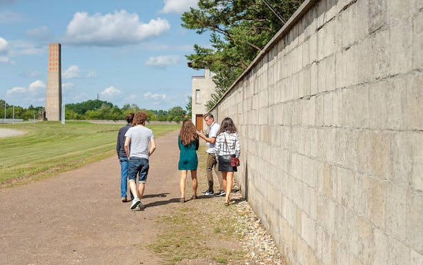 Tour group at Sachsenhausen Concentration Camp Memorial with guide explaining historical significance.