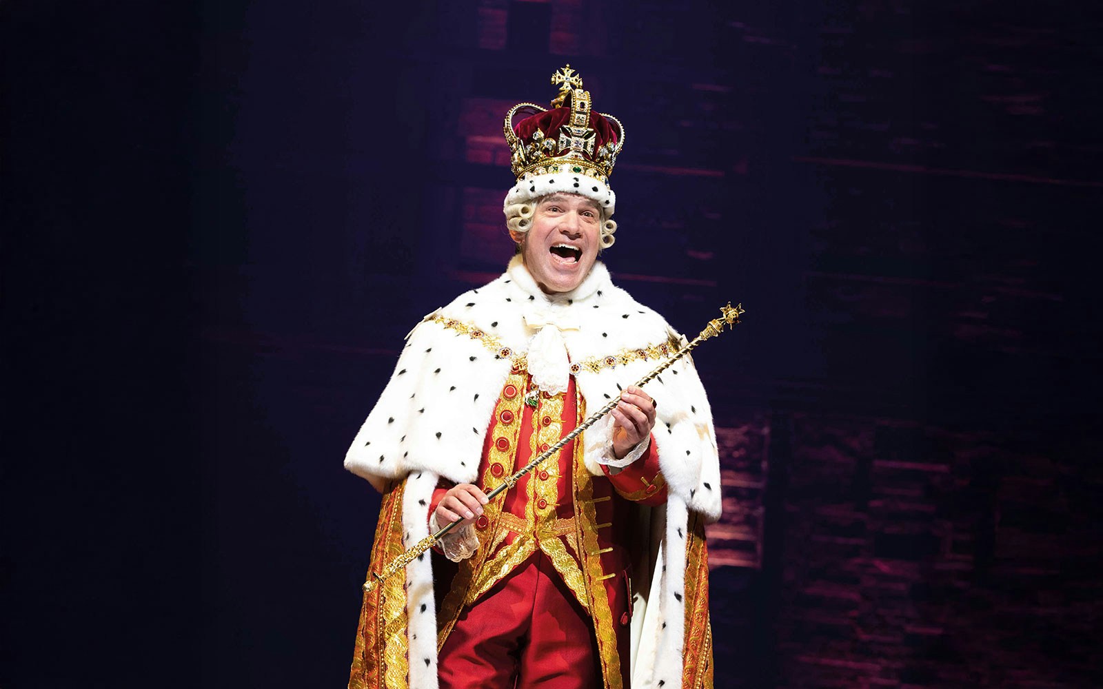 Performer in royal costume during Hamilton musical scene.