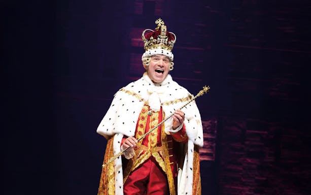 Performer in royal costume during Hamilton musical scene.