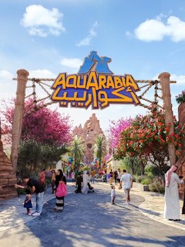Entrance to Aquarabia theme park with visitors and colorful decorations.