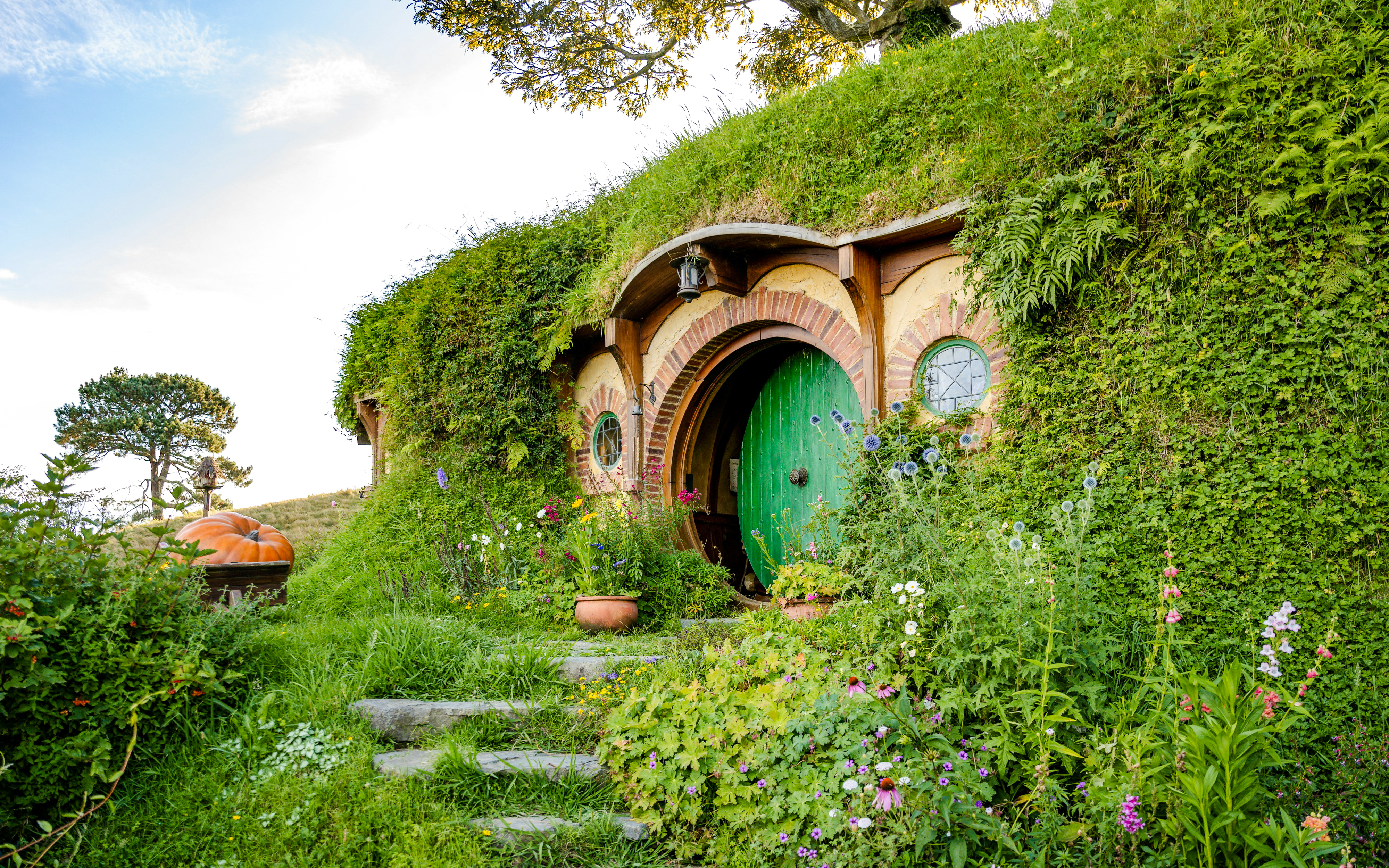 Bag End hobbit hole with green door and garden, Hobbiton movie set tour.