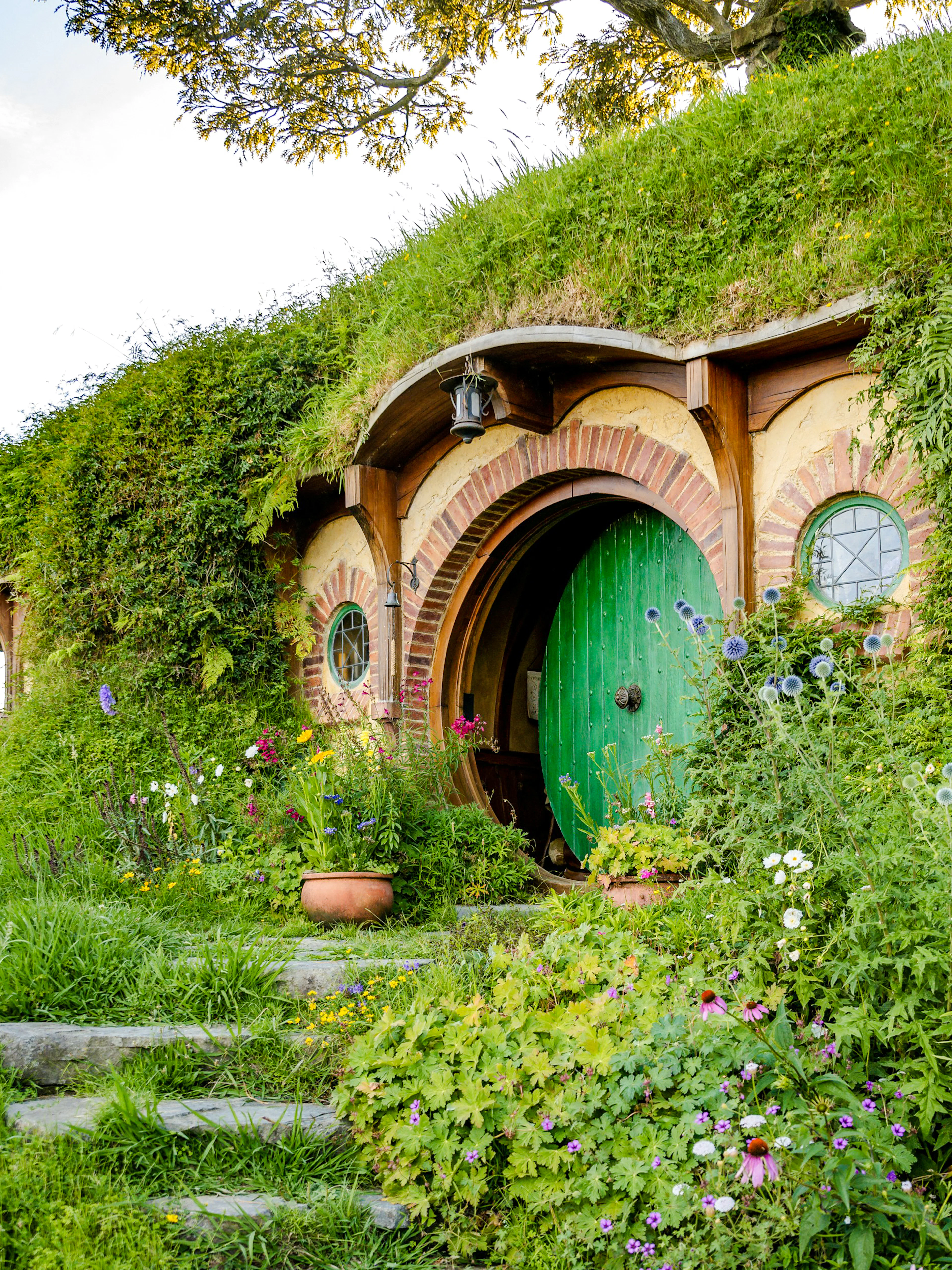 Bag End hobbit hole with green door and garden, Hobbiton movie set tour.