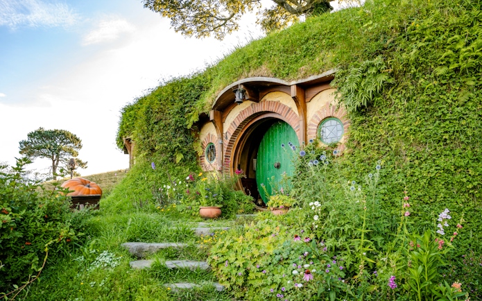 Bag End hobbit hole with green door and garden, Hobbiton movie set tour.