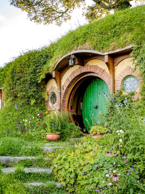 Bag End hobbit hole with green door and garden, Hobbiton movie set tour.