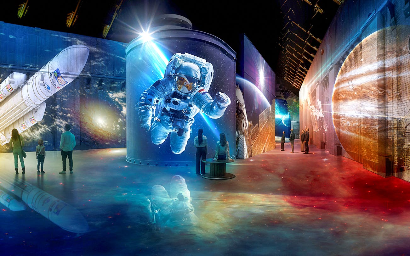 Immersive space-themed exhibit with projections of an astronaut and planets at Fabrique des Lumières.