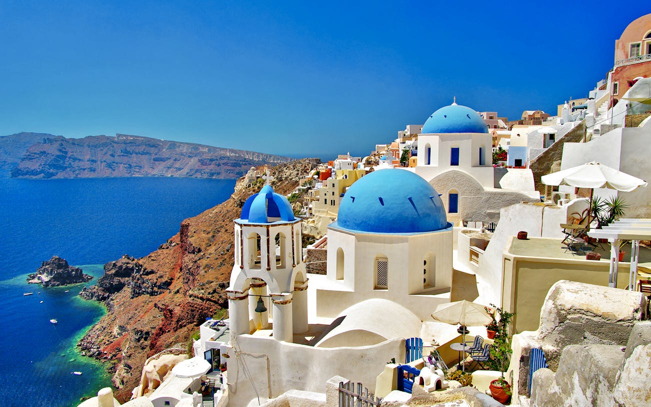 Santorini's blue-domed churches overlooking the Aegean Sea, Oia, Greece.