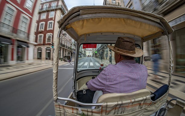 Private electric tuk tuk driving through city streets on a half-day guided sightseeing tour.