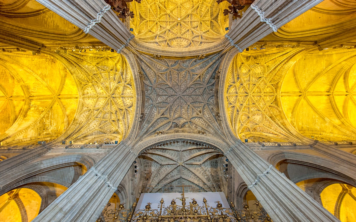 Seville Cathedral's ornate ceiling and arches, showcasing intricate Gothic architecture.