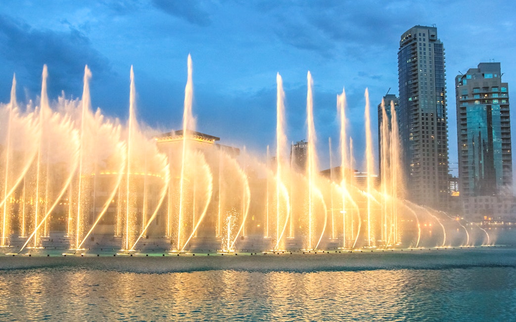 Dubai Fountain Boardwalk with illuminated water jets and city skyline.